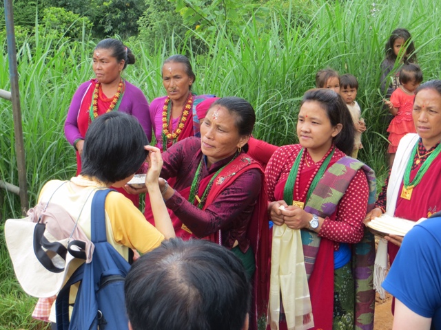 民族衣装で出迎えてくれた村の女性から、歓迎のティカを付けてもらうメンバー