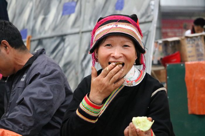 商売の合間に果物をほおばるランテンザオ族の女性(メオバック市場にて)