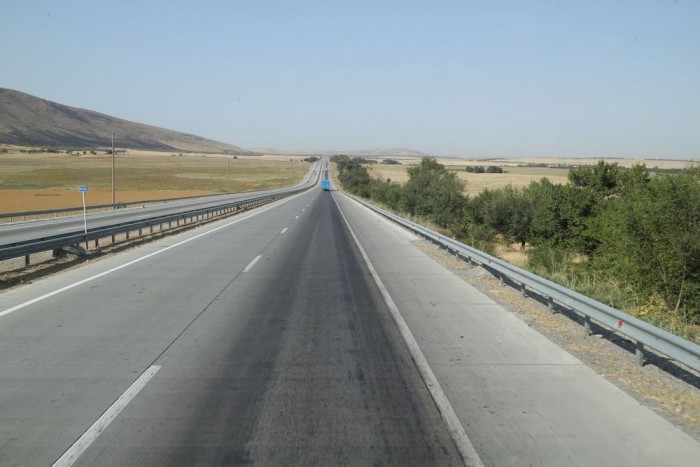 カザフスタンは広大な平原を有し道もまっすぐです、左に見える丘は天山山脈の西の端